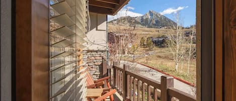 A wooden porch with a stone wall and a view of mountains.