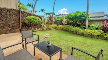 A patio with a stone wall, a table with chairs, and a small flower arrangement.