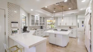 Et moderne køkken med hvide skabe, en stor ø og et backsplash med hexagonmønster.