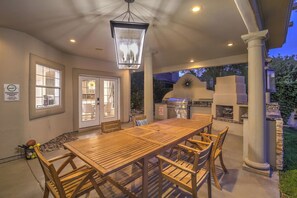 An outdoor patio with a wooden table and chairs, a grill, and a stone fireplace. - 5700 sqft Lux Golf Villa w Pool & Spa Near Strip (Henderson)