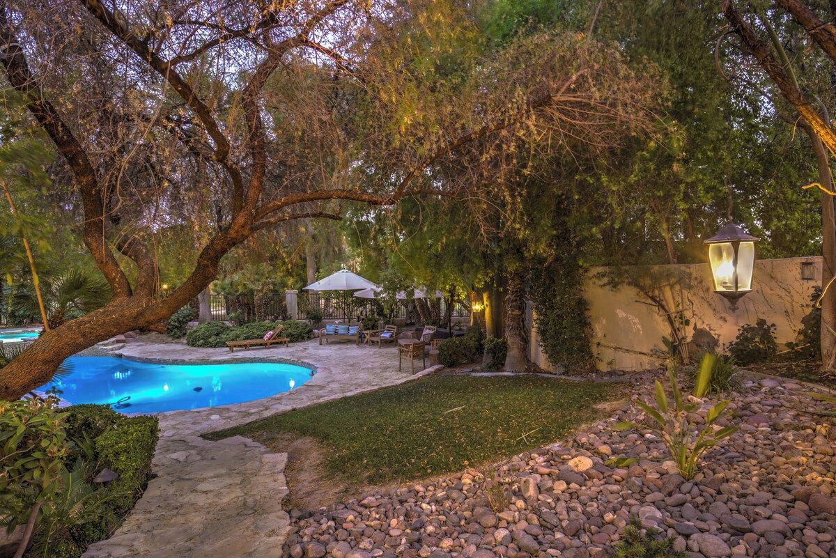 Ein Swimmingpool, umgeben von einem Garten mit einer Terrassenanlage und Gartenmöbeln.