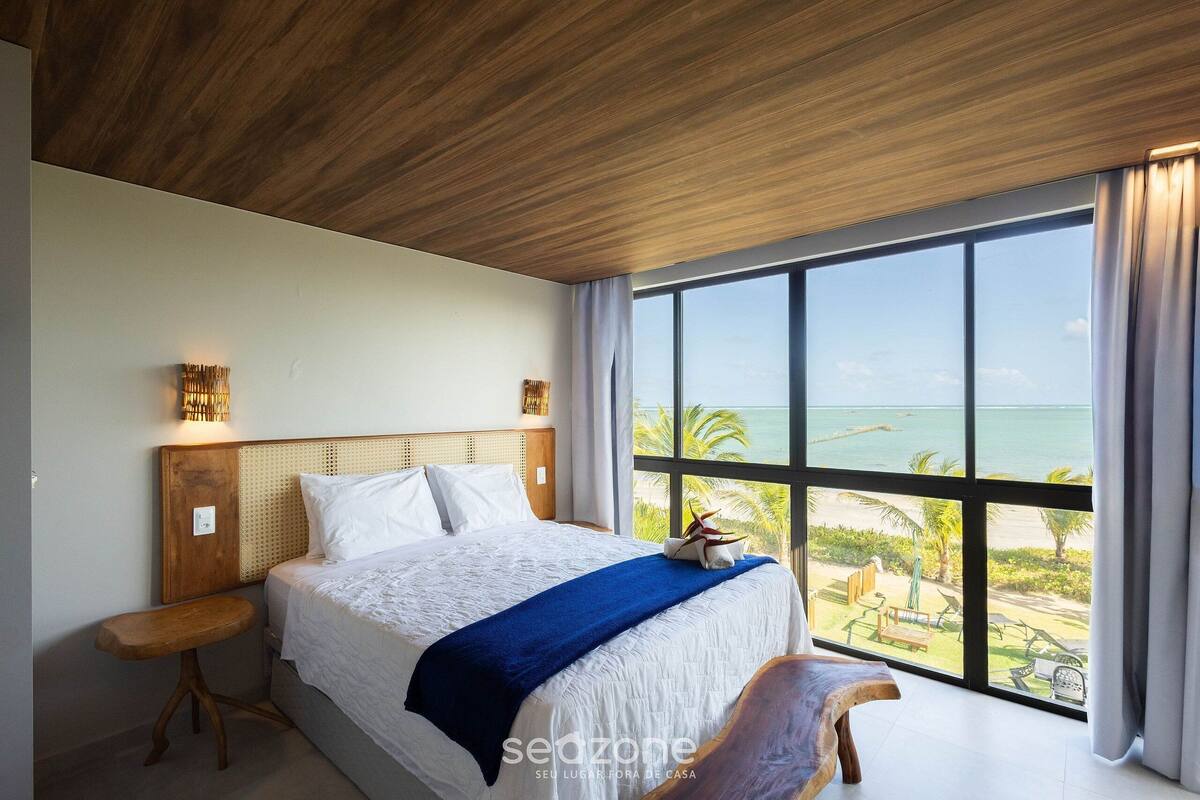 Un dormitorio con un ventanal que ofrece vistas a la playa y al océano.