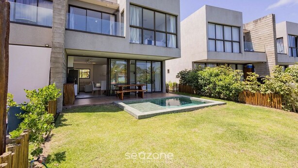 Una casa moderna de dos pisos con piscina, ventanas amplias y un área de patio.