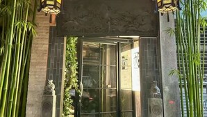 Una entrada de estilo tradicional con techo de tejas, dos faroles ornamentales y una estatua a cada lado.