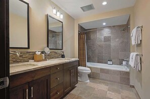 Een moderne badkamer met een grote spiegel, een wastafelmeubel met een wastafel, een toilet en een douchehoek.