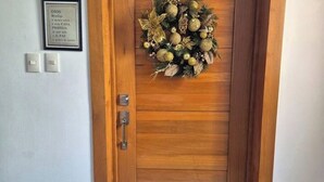 Una puerta de madera con un adorno festivo y un cartel enmarcado encima.