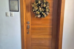 A wooden door with a decorative wreath and a framed sign above it. - Dona Antonia Terrace near Carrefour (Santo Domingo)