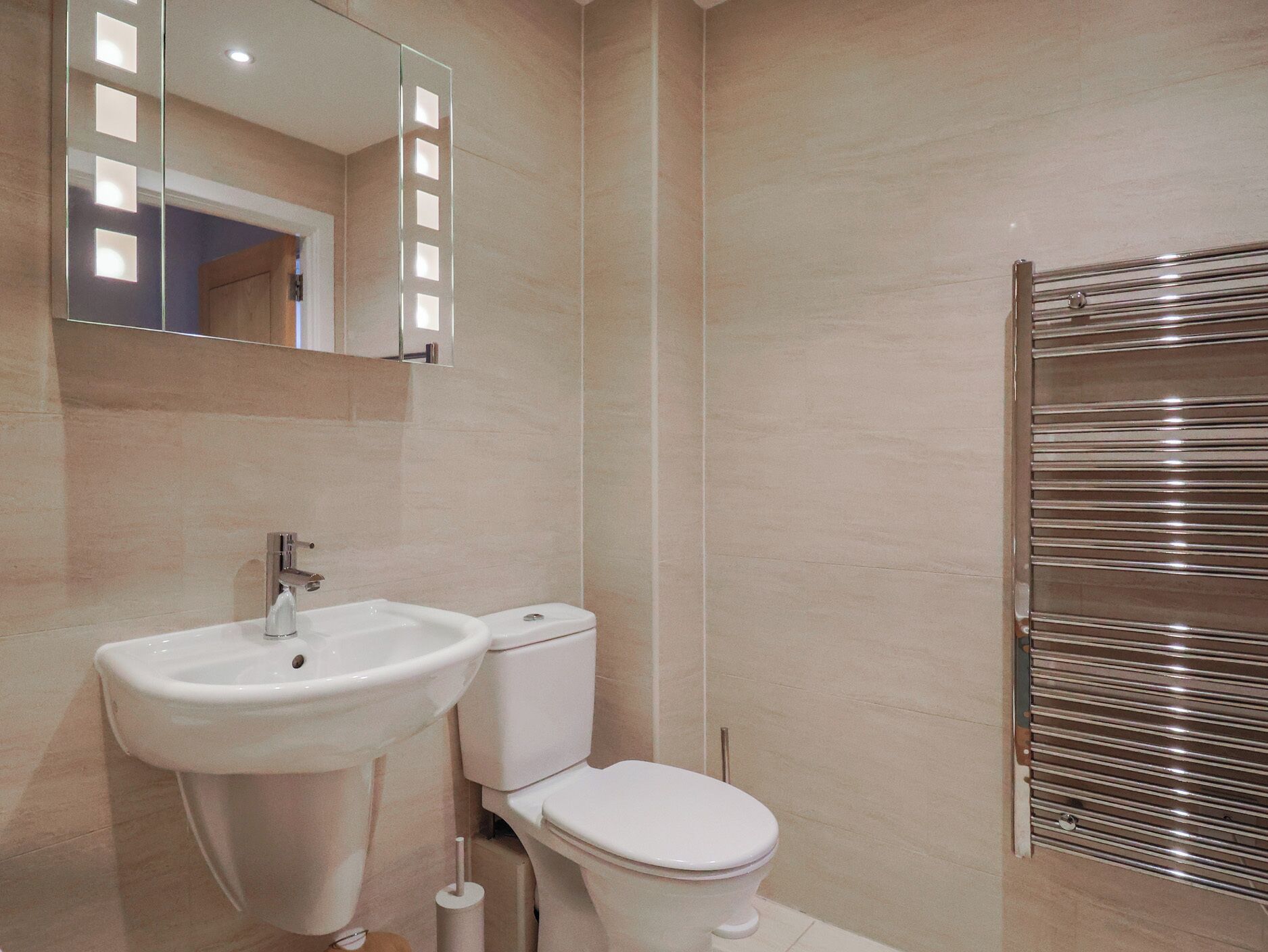 A bathroom with a sink, toilet, and a towel rack.
