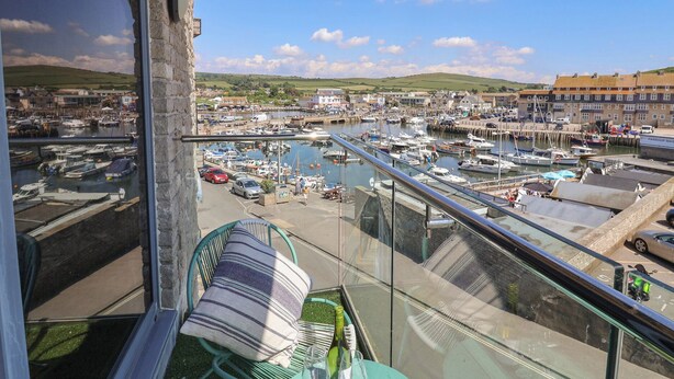 Een balkon met uitzicht op een jachthaven, boten en gebouwen.