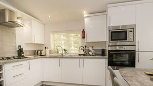Una cocina moderna con gabinetes blancos, electrodomésticos de acero inoxidable y un suelo de madera con diseño de espiga.