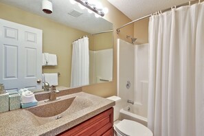 A bathroom with a sink, mirror, toilet, and shower curtain. - Pico Mountain Condo F106 3 Bedroom Home (Killington)
