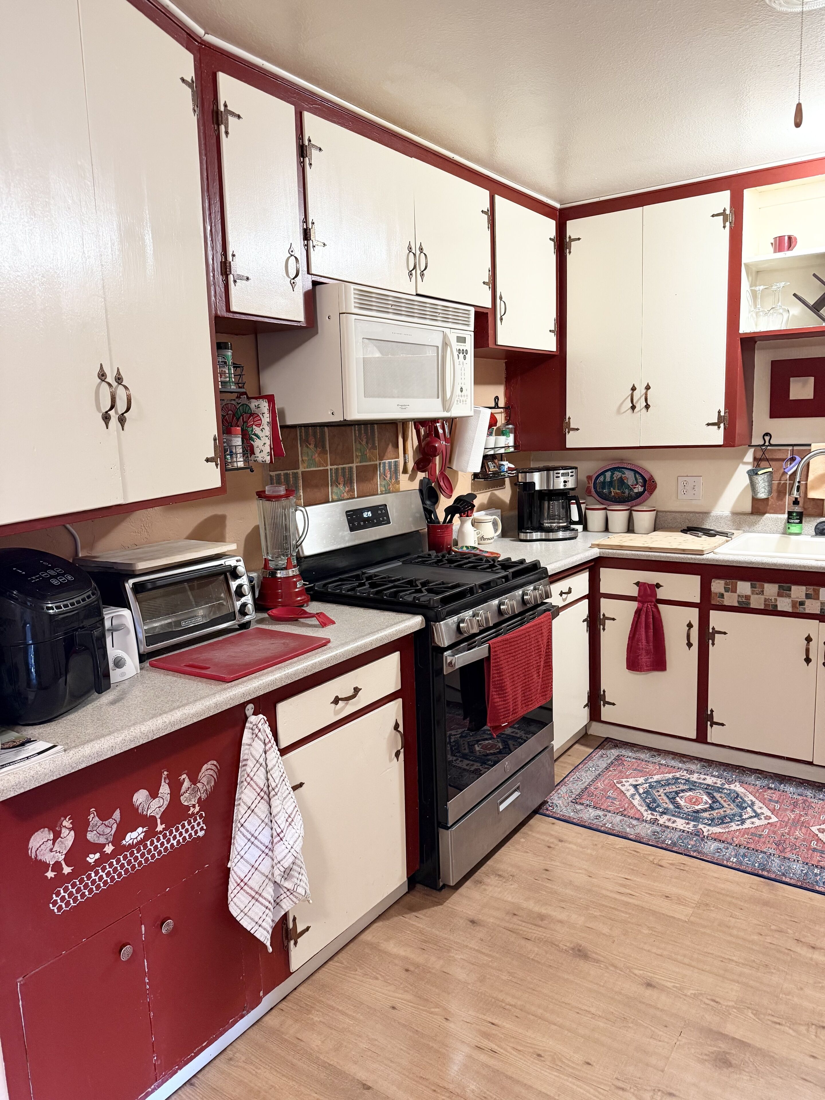 A kitchen with a stove, microwave, toaster, and various utensils.