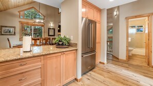 A kitchen with wooden cabinets, a stainless steel refrigerator, and a granite countertop. - Woodlands House 3 Bedroom Home (Truckee)