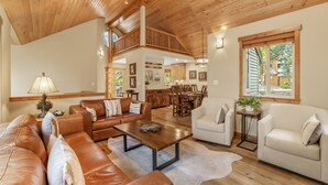 A spacious living area with leather sofas, a wooden coffee table, and a dining area with wooden furniture. - Woodlands House 3 Bedroom Home (Truckee)