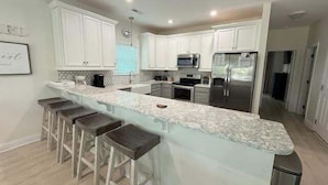 Una cocina moderna con armarios blancos, encimera de granito y electrodomésticos de acero inoxidable.