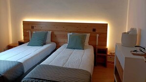A room with two single beds, wooden headboards, bedside tables, and a small desk with a chair. - House of Rising Sun (Remédios, Ponta Delgada)