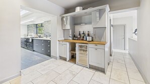 A modern kitchen with grey cabinets, a wooden countertop, and a built-in wine fridge.