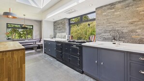 A modern kitchen with a large island, dark cabinetry, and a stone accent wall.