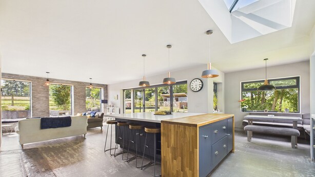 A modern kitchen with a large island, bar stools, and pendant lighting.