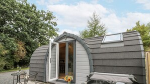 A spa-like structure with a hot tub, a small patio with chairs, and a door leading to an interior space. - Oak View (Rhayader)