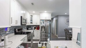 A modern kitchen with white cabinets, stainless steel appliances, and a tiled backsplash. - Villa in Corolla Light with Views, Hot Tub & More! (Corolla)