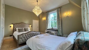 A bedroom with a large bed, a smaller bed, a desk, and a window with curtains. - Your Country House (Reading)