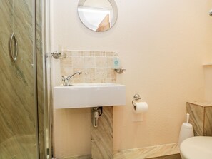 A bathroom with a marble sink, a toilet, and a shower area. - The Burrow (Windermere)