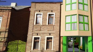 A two-story building with a brick facade and a green entrance. - Hotel Somi Inn (Tbilisi)