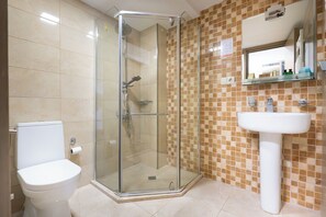 A bathroom with a glass-enclosed shower, a white sink, and a toilet. - Hotel Somi Inn (Tbilisi)