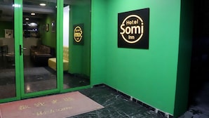A green-walled hotel entrance with a glass door, a welcome mat, and two illuminated signs reading "Hotel SOMI Inn". - Hotel Somi Inn (Tbilisi)