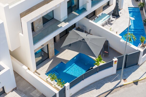 Ein modernes Gebäude mit Pool auf dem Dach, Außenbereich zum Sitzen und einer Glasbrüstung.