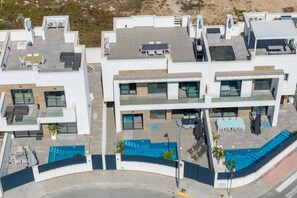 Ein modernes, mehrstöckiges Gebäude mit Dachterrassen, Sitzbereichen im Freien und einem Swimmingpool.