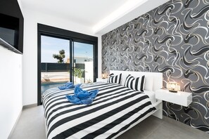 Ein modernes Schlafzimmer mit einem großen Bett, Blick auf einen Swimmingpool und einer Wand mit Muster.