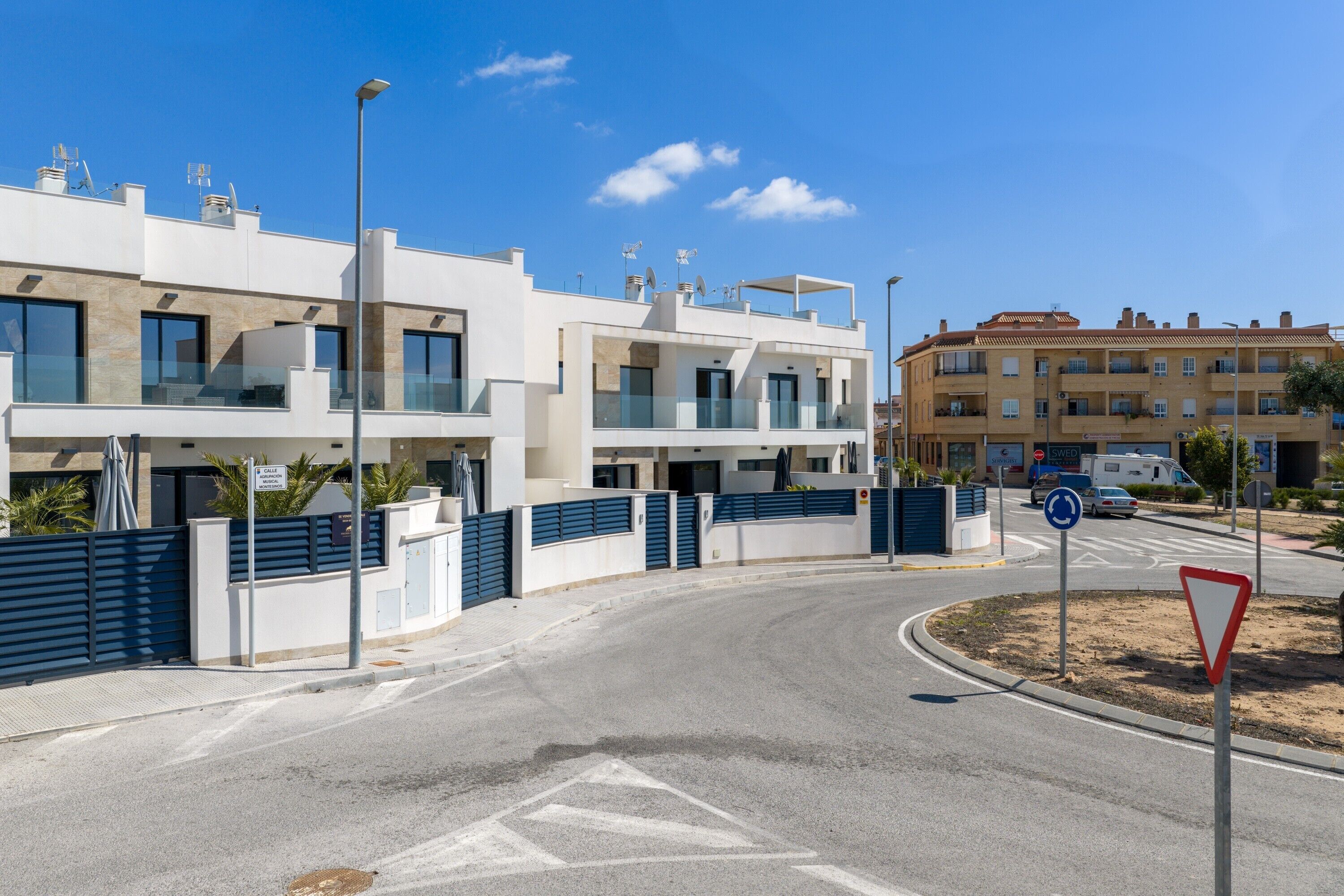 Un bâtiment moderne doté de balcons, d’une entrée sécurisée et surplombant un ciel dégagé.