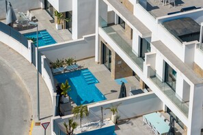 Een modern gebouw met een zwembad op het dak, terras en een helder uitzicht op de omgeving.