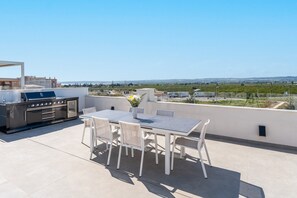 A rooftop terrace with a grill, dining table, and chairs, overlooking a landscape. - Modern Villa with Private Pool, Wi-Fi, and Air Conditioning – R-40-B Holiday Home (Montesinos)