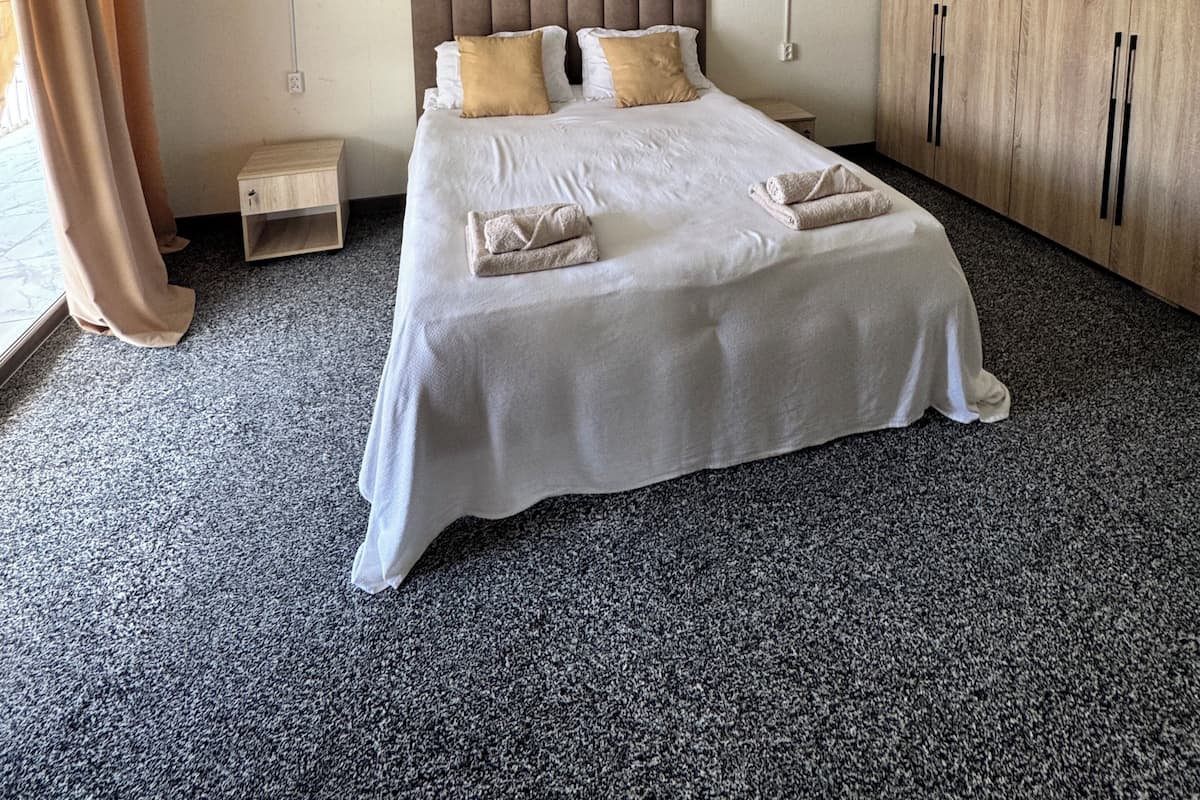 Un dormitorio con cama, mesitas de noche, un armario y una lámpara colgante.
