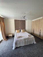 Quarto com cama, mesas de cabeceira, guarda-roupa e luminária pendente.