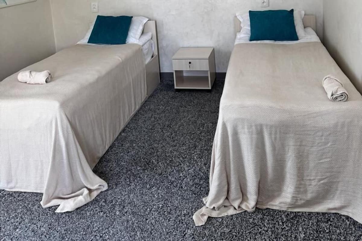 Habitación de hotel con dos camas, decoración de pared de mármol, una araña y un reloj.