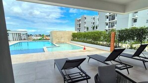 Un espace piscine aménagé sur le toit, avec des chaises longues et une vue sur un immeuble d’habitation.