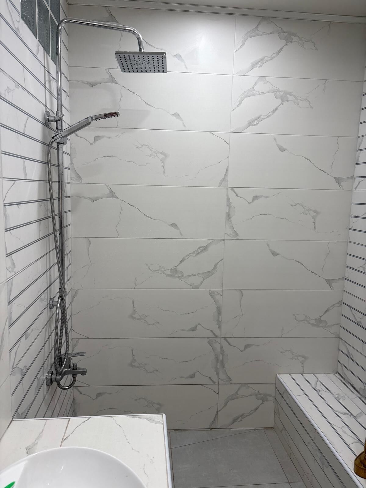 A bathroom with a shower, a sink, and a bench.