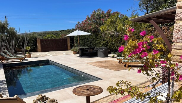 Une piscine avec des chaises longues et une pergola.