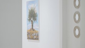 Una habitación con pared blanca, un cuadro de un árbol y tres adornos circulares en la pared.