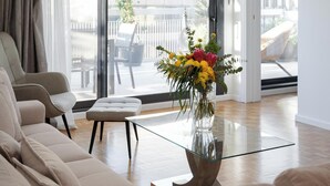 Un salón amplio con una lámpara araña moderna, una mesa de centro de vidrio y un sofá.