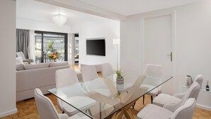 Una sala de estar moderna con una mesa de comedor de vidrio, sofás blancos y un televisor de pantalla plana.