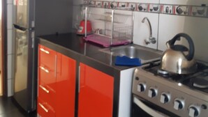 Cuina amb armaris vermells, nevera d'acer inoxidable, una olla a la cuina i microones damunt de la cuina.