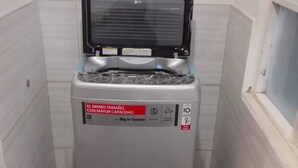 Assecadora plata compacta de càrrega frontal, amb panell de control i etiqueta d'advertència.