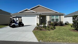 Einbungalow mit Garage, Auffahrt und Golfwagen davor.
