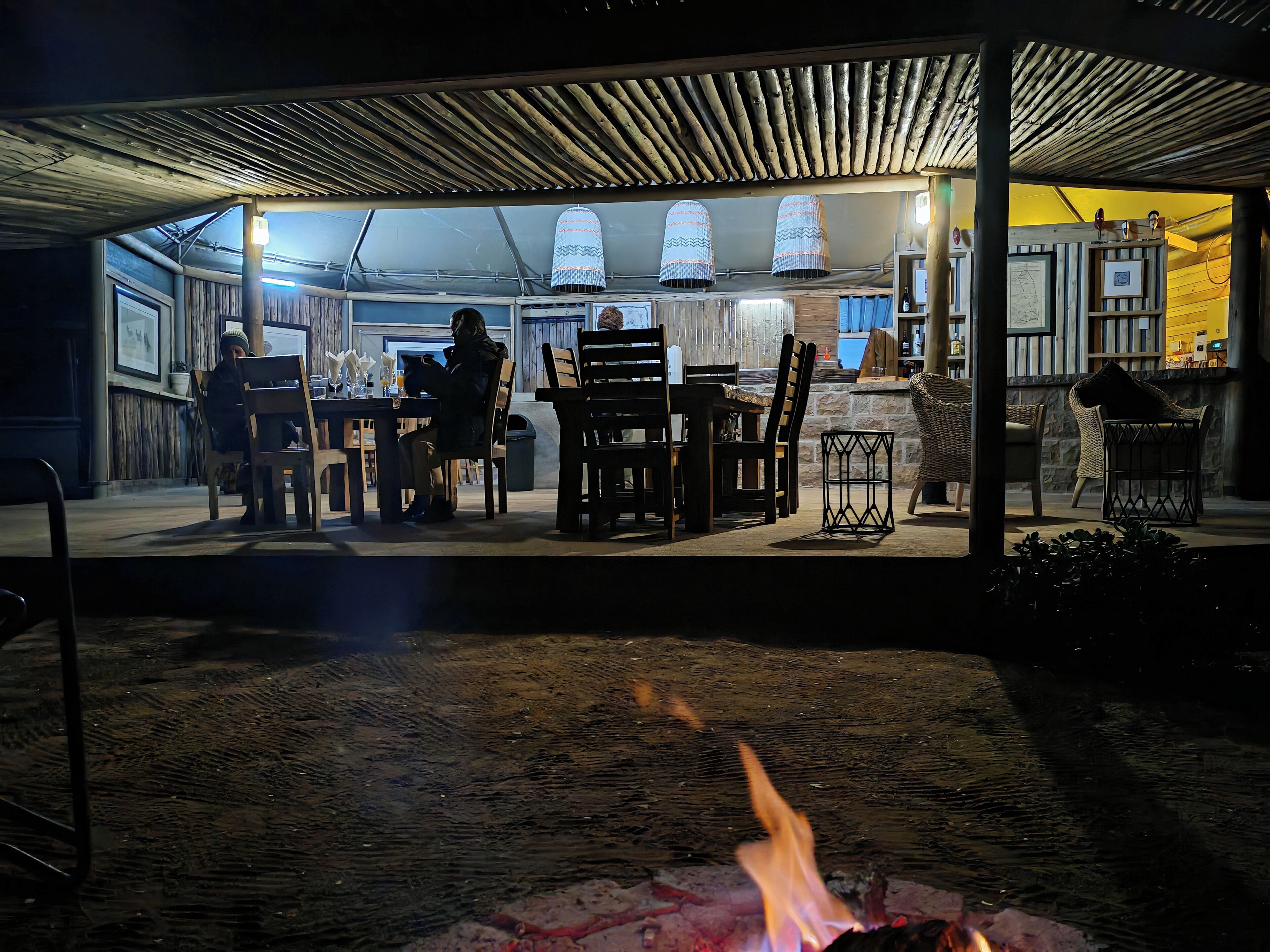 An outdoor dining area with wooden furniture and a fire pit.
