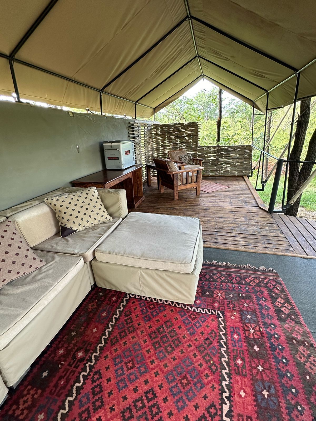 Een tent met een bank, een voetenbankje en een bijzettafeltje met een radio.